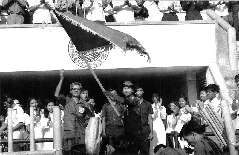 Đồng chí Võ Văn Kiệt, Chủ tịch Ủy ban nhân dân Cách mạng Thành phố Sài Gòn – Gia Định trao cờ truyền thống của Đoàn Thanh niên Cộng sản Hồ Chí Minh cho đồng chí Phạm Chánh Trực, Bí thư Thành Đoàn Thành phố trong ngày ra quân của Lực lượng Thanh niên Xung phong tại Sân vận động Thống Nhất, ngày 28 tháng 3 năm 1976 - Ảnh: Tư liệu