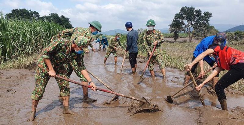 Lực lượng chiến sĩ đang giúp người dân vét bùn, làm sạch đường. (Ảnh: PLO)