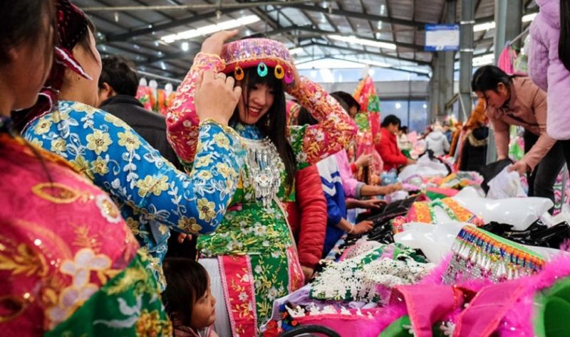 Một cô gái đang thử khăn đội đầu, loại trang sức truyền thống của người dân tộc Mông thường được sử dụng trong các dịp lễ hội.