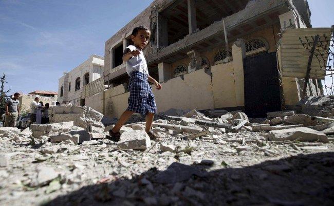 Cậu bé đang đi bộ tại ngôi nhà bị hư hỏng do cuộc không kích Saudi dẫn đầu ở thủ đô Yemen, Sanaa